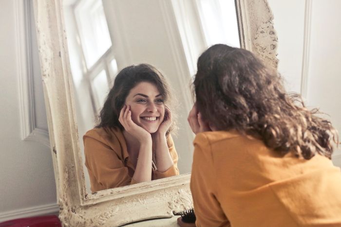 Young woman smiling at herself in the mirror